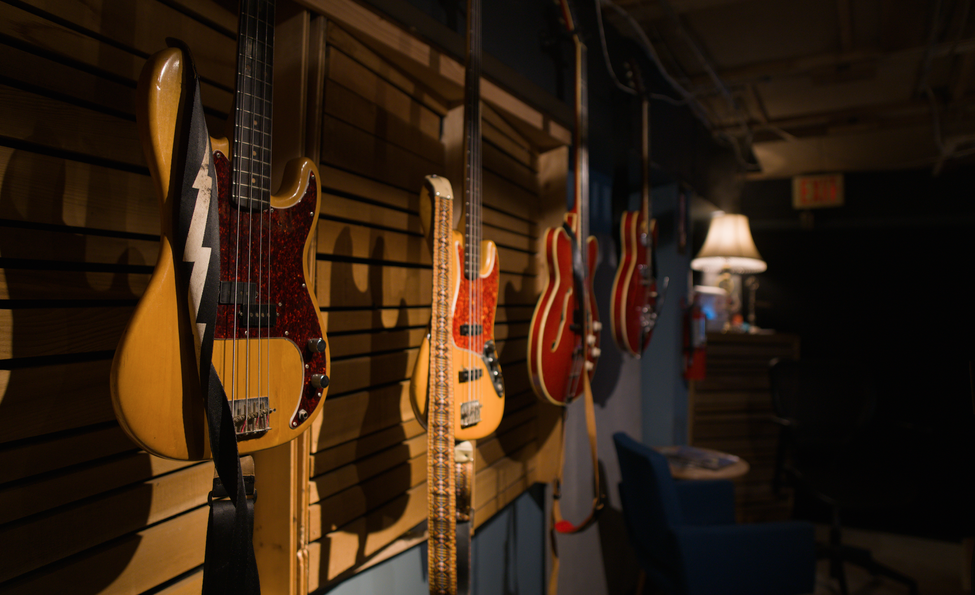three basses and one guitar hanging in mood lighting